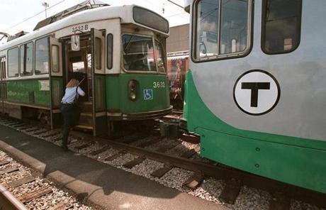 Newton, MA--5/29/96--GREEN LINE PAINT JOB--So far 11 of the 95 Green Line MBTA cars have been painted with the new colors - Atlanta Green and Platinum Mist (right). A T worker climbs aboard a yet-to-be painted car in the yard of the Riverside station.
